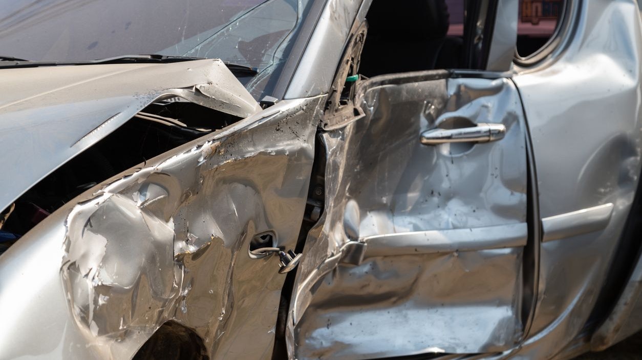Close-up of silver car damaged in accident.
