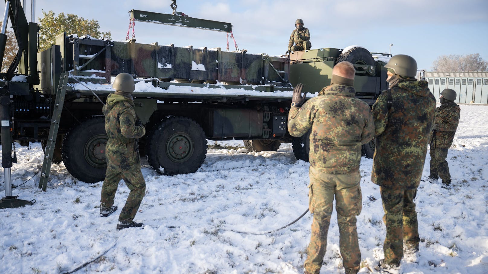 Teilnehmer und ein Ausbilder der deutschen Bundeswehr vor einem Lastwagen mit Containern für einen Patriot-Werfer während eines Lehrgangs für ukrainische Soldaten am Patriot-Luftabwehrsystem.