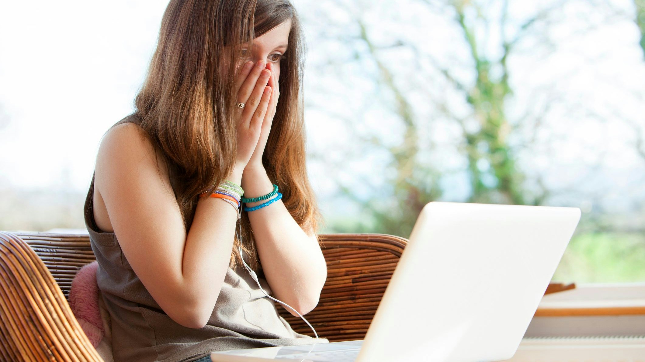 Teenage girl with hands on face victim of cyber bullying