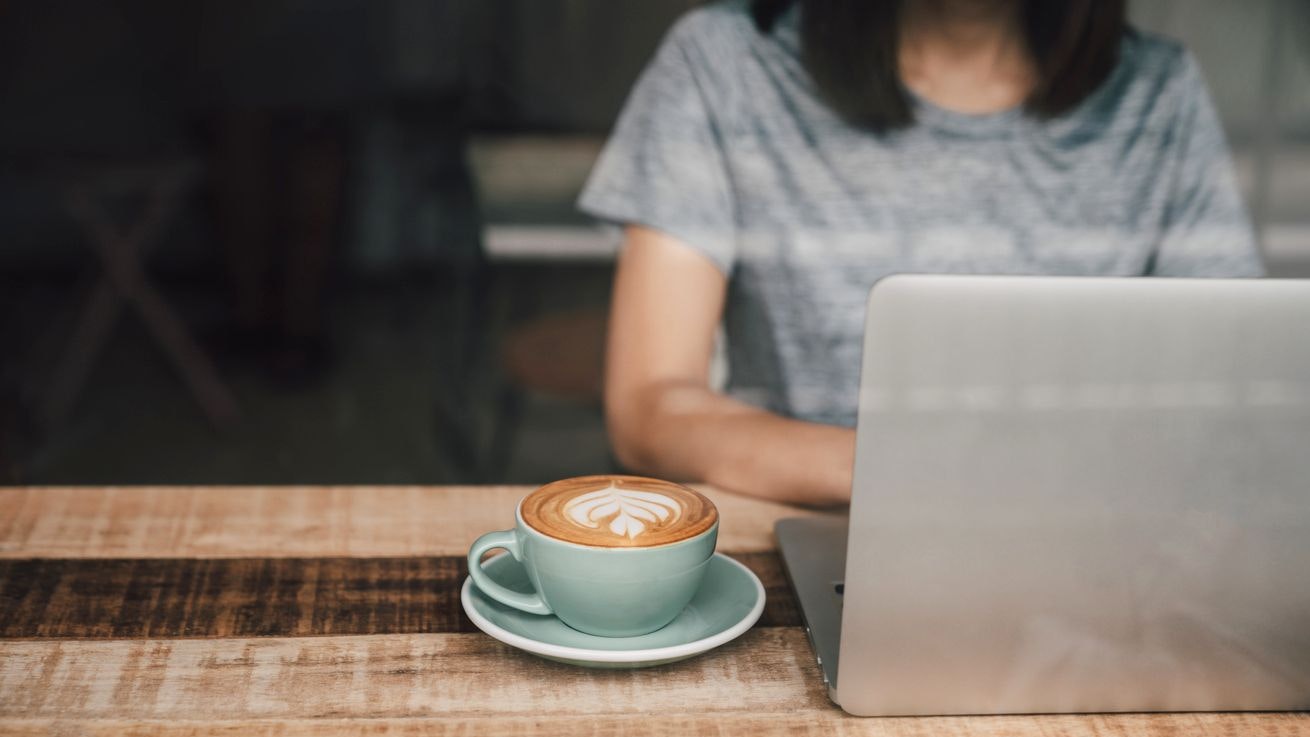 Beautiful woman using laptop at cafe. Confident young woman in smart casual wear working on laptop while sitting near window in creative office or cafe