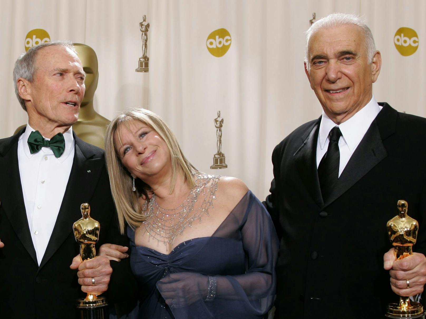 Clint (ganz links) wird von Barbra Streisand umarmt, nachdem er mit Produzenten Al (ganz rechts) einen Oscar für "Million Dollar Baby" gewonnen hat.