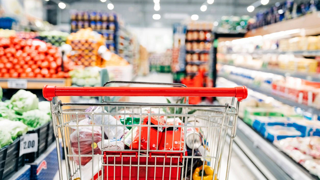 Shopping cart in grocery store. Shopping cart with various groceries in supermarket aisle.