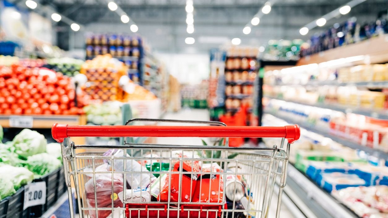 Shopping cart in grocery store. Shopping cart with various groceries in supermarket aisle.