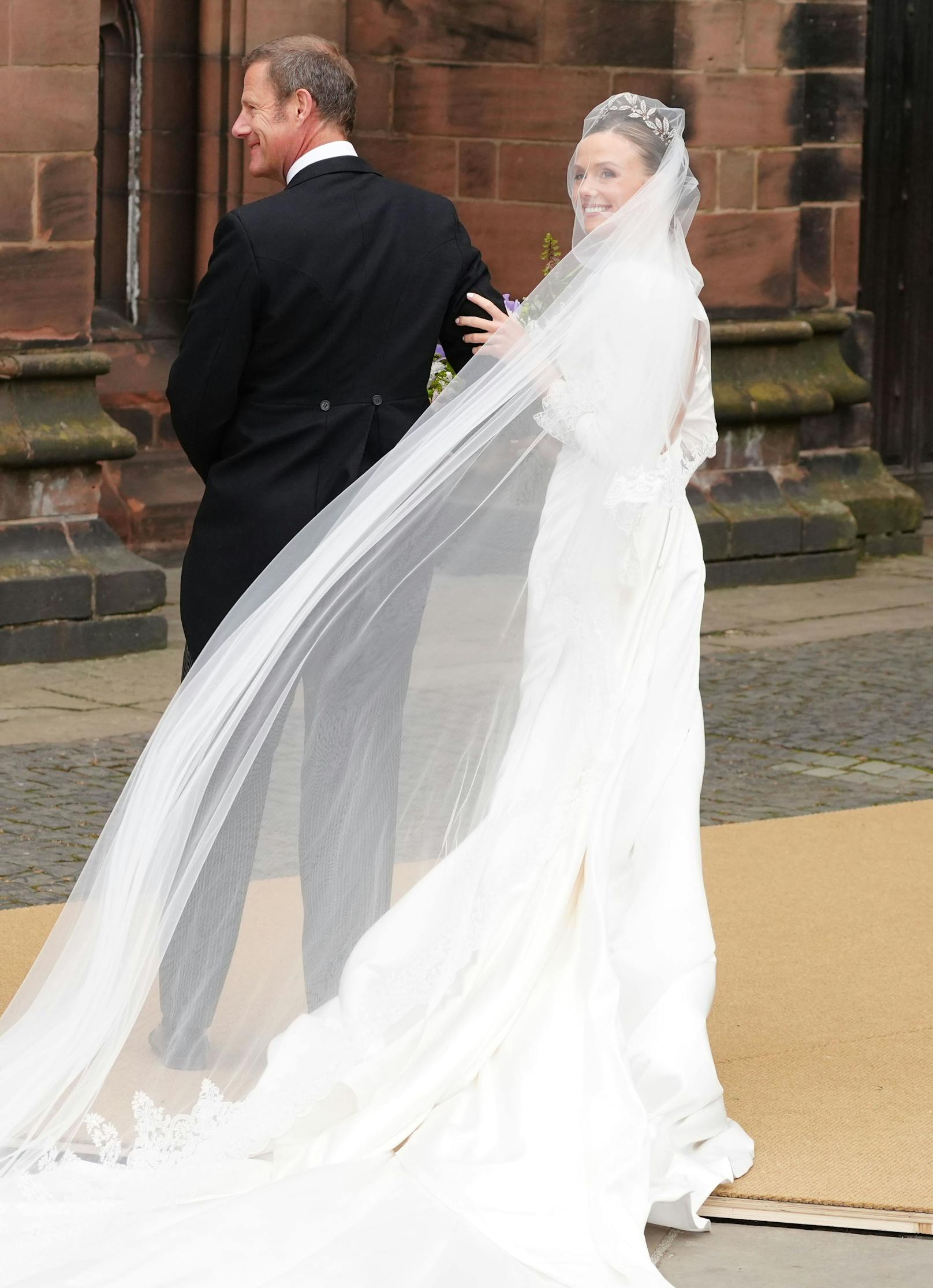 Strahlend wird die Braut am Arm ihres Vaters Rupert Henson zur Zeremonie begleitet.