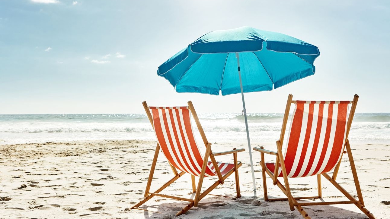 Still life shot of two deck chairs under an umbrella on the beach