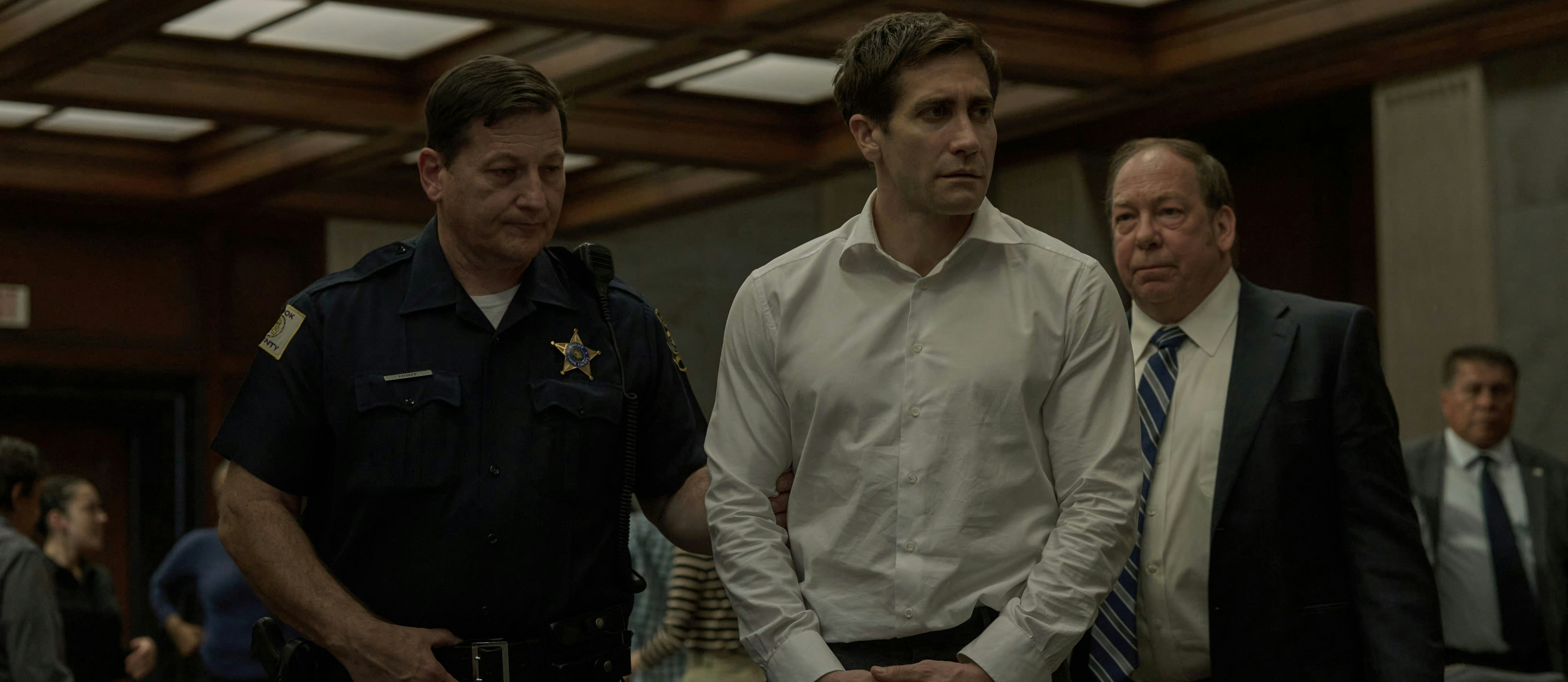 Gleich klicken die Handschellen: Staatsanwalt Rusty Sabich (Jake Gyllenhaal, Mitte) wird verdächtigt, seine Kollegin und Geliebte getötet zu haben. Sein Chef Raymond Horgan (Bill Camp, re.) kann nur tatenlos zusehen. Die Serien-Verfilmung des Thrillers "Aus Mangel an Beweisen" von Scott Turow startet am 12. Juni auf Apple TV+