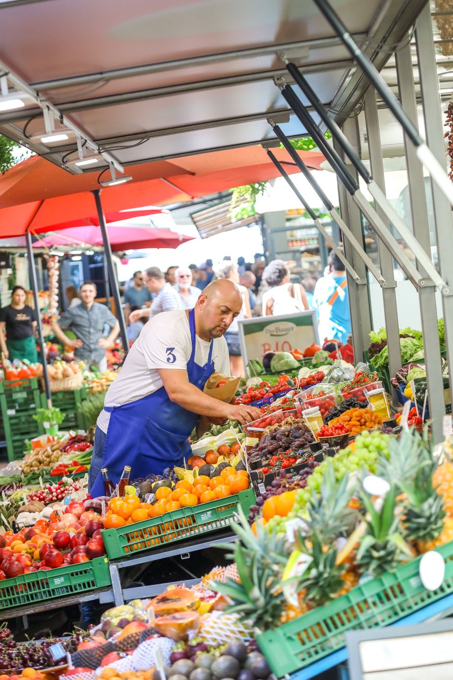 Wiener Marktstandler beim Prüfen der angebotenen Waren vor seinem Marktlokal