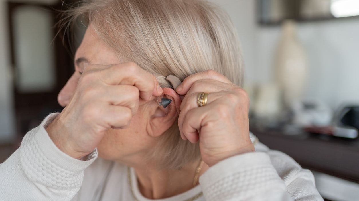 Old Woman Holding A Hearing Aid