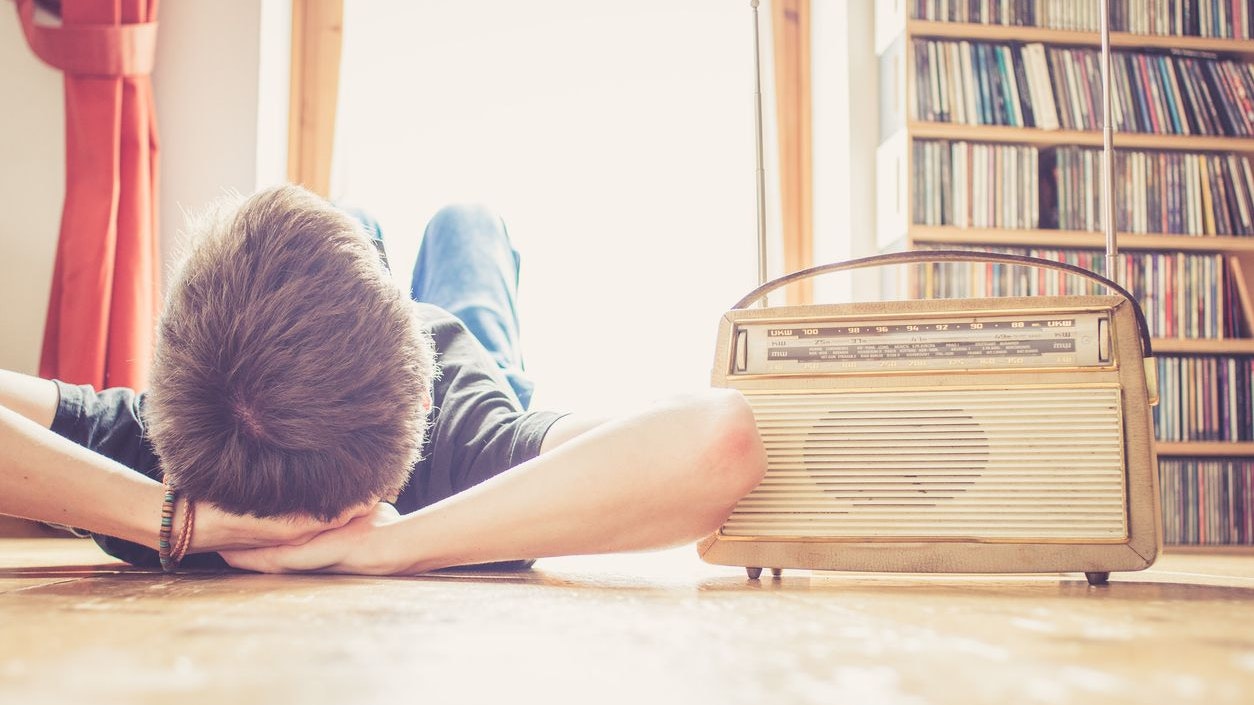 Young man lying on the floor is listening to a vintage radio, free time