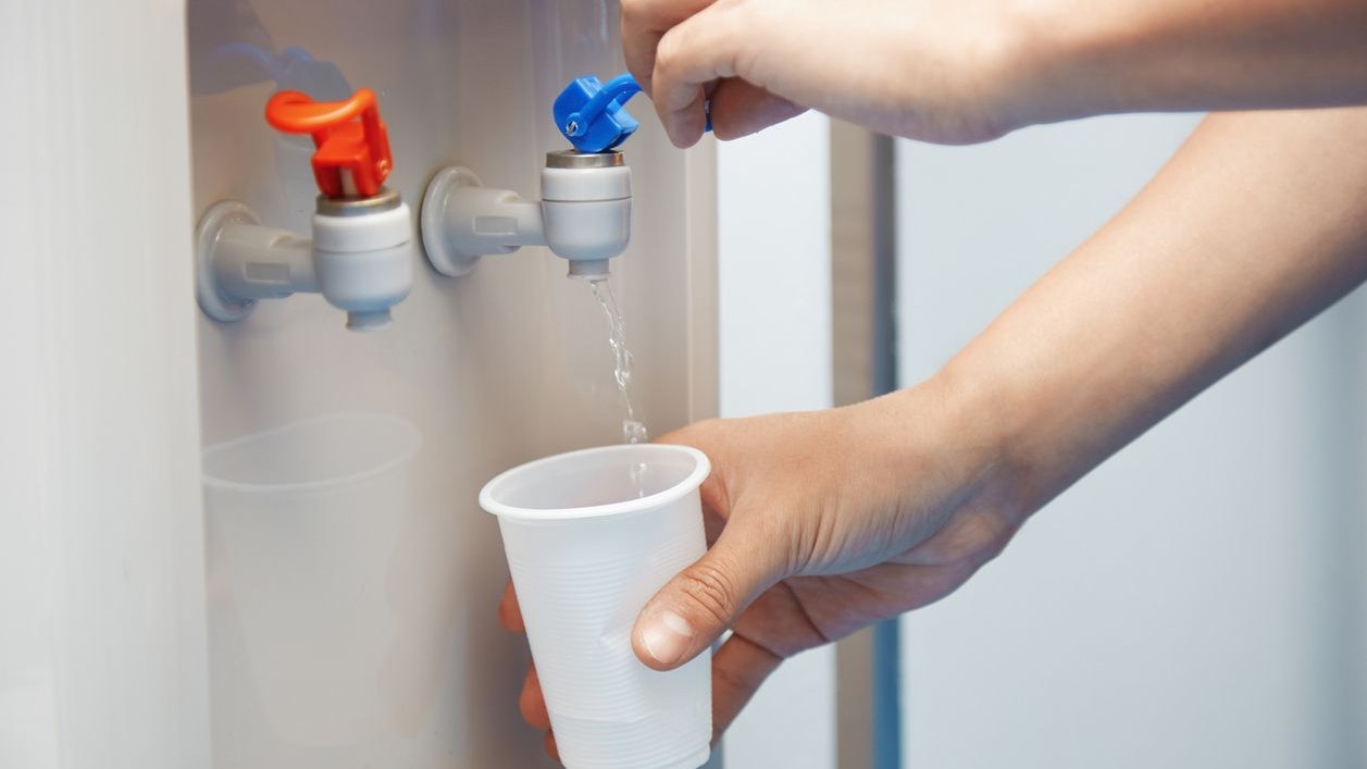 Man filling plastic cup at water cooler