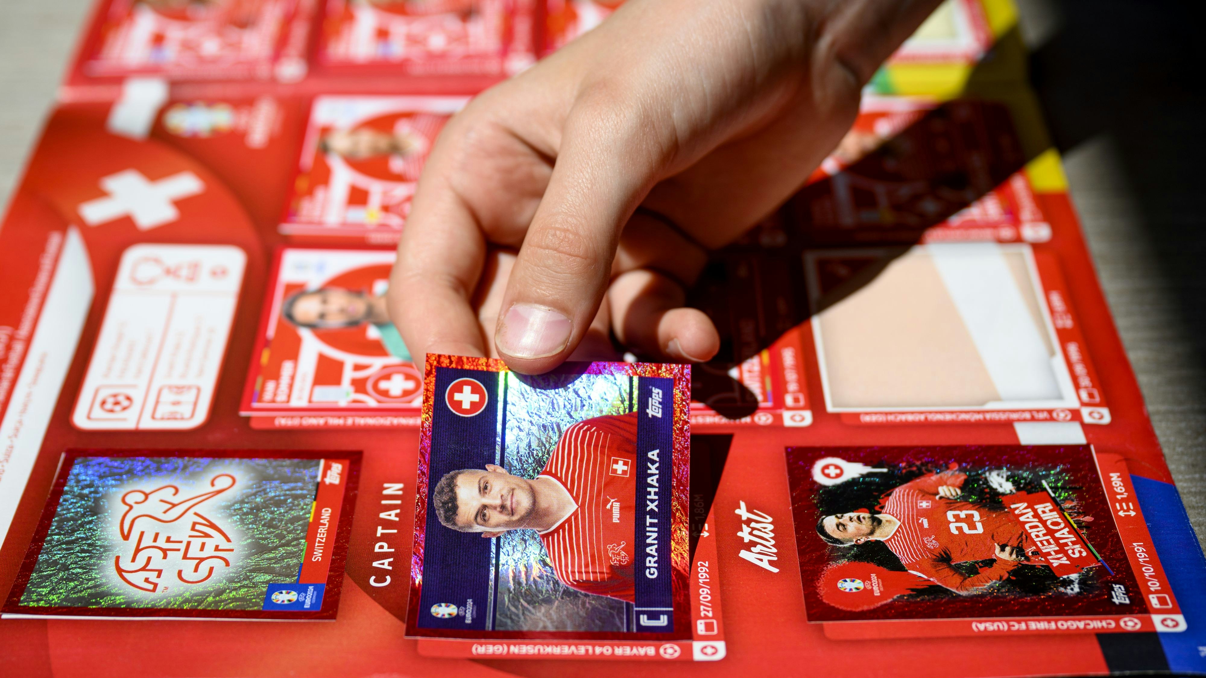 Download von www.picturedesk.com am 19.06.2024 (13:12).  A young collector sticks a Topps Euro 2024 sticker of the Switzerland's soccer national team (Granit Xhaka) in the official Topps album of the UEFA Euro 2024 Germany, in Lausanne, Friday, May 17, 2024. Switzerland's head coach Murat Yakin announces today in Lausanne the Swiss squad for the UEFA EURO 2024. (KEYSTONE/Laurent Gillieron) - 20240517_PD6138 - Rechteinfo: Rights Managed (RM)