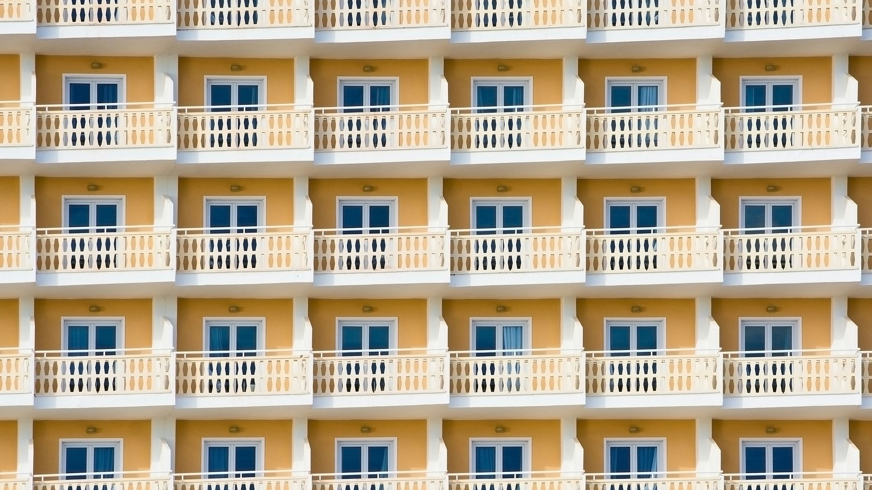 Yellow hotel exterior with small balconies and windows tourism background, Spain.