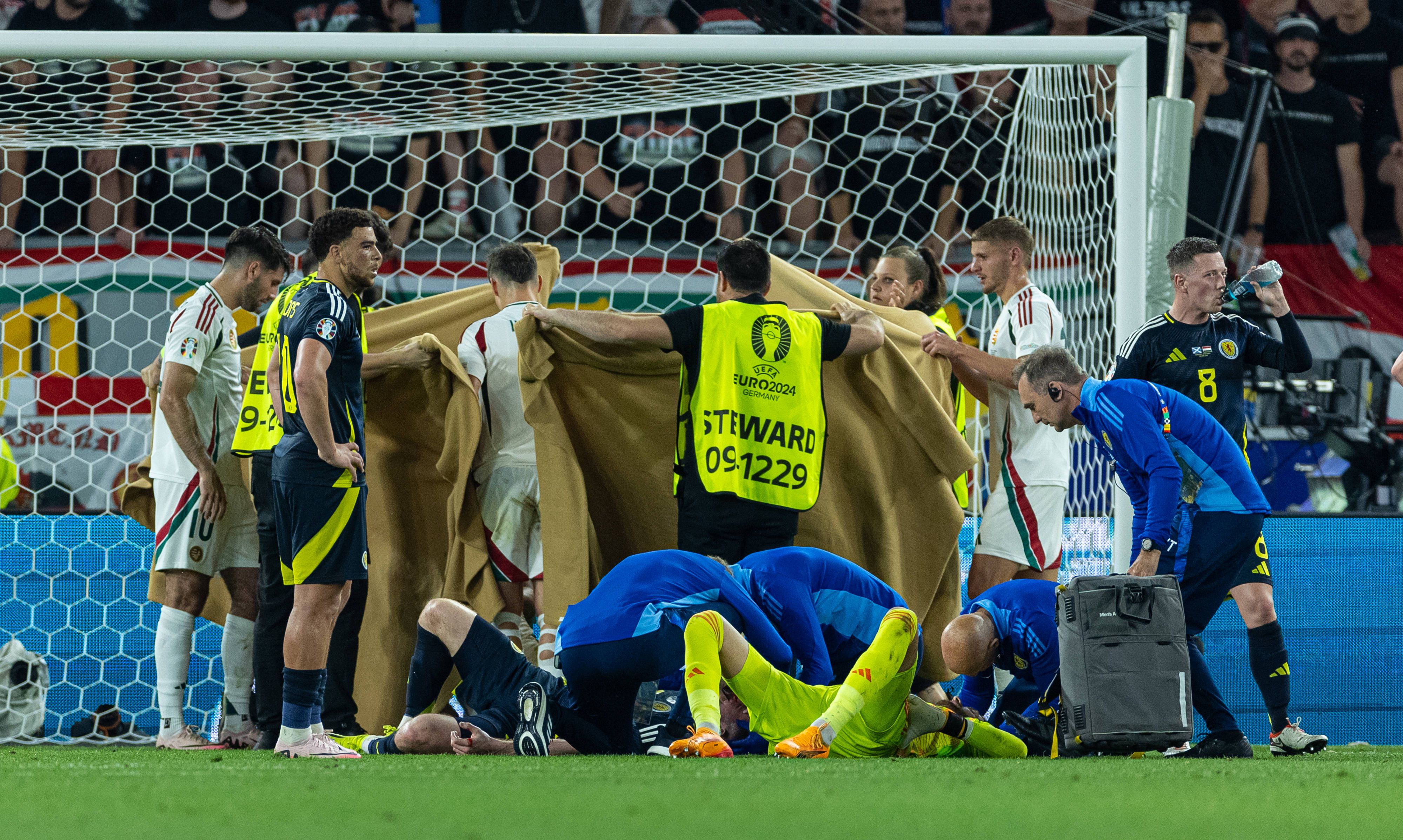 Varga wird versorgt, mit Decken abgeschirmt.