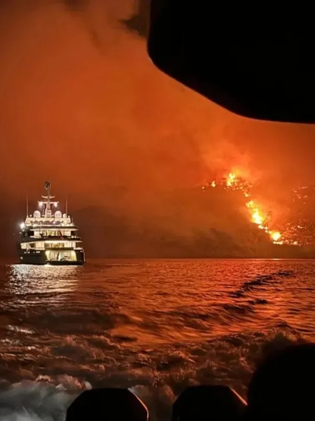 Die Feuerwehr postete auf Facebook diese Yacht - im Hintergrund ist die Feuersbrunst an Land zu sehen.