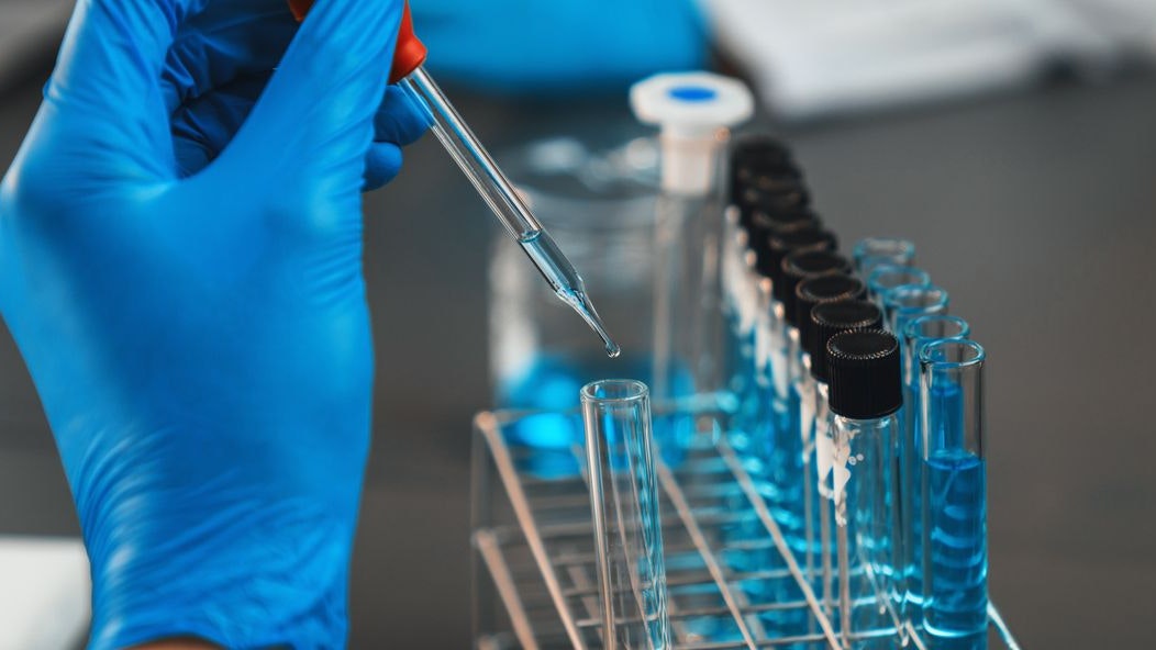 Scientist conduct chemical experiment in medical laboratory, carefully drop precise amount of liquid from pipette into test tube for vaccine drug or antibiotic development. Neoteric