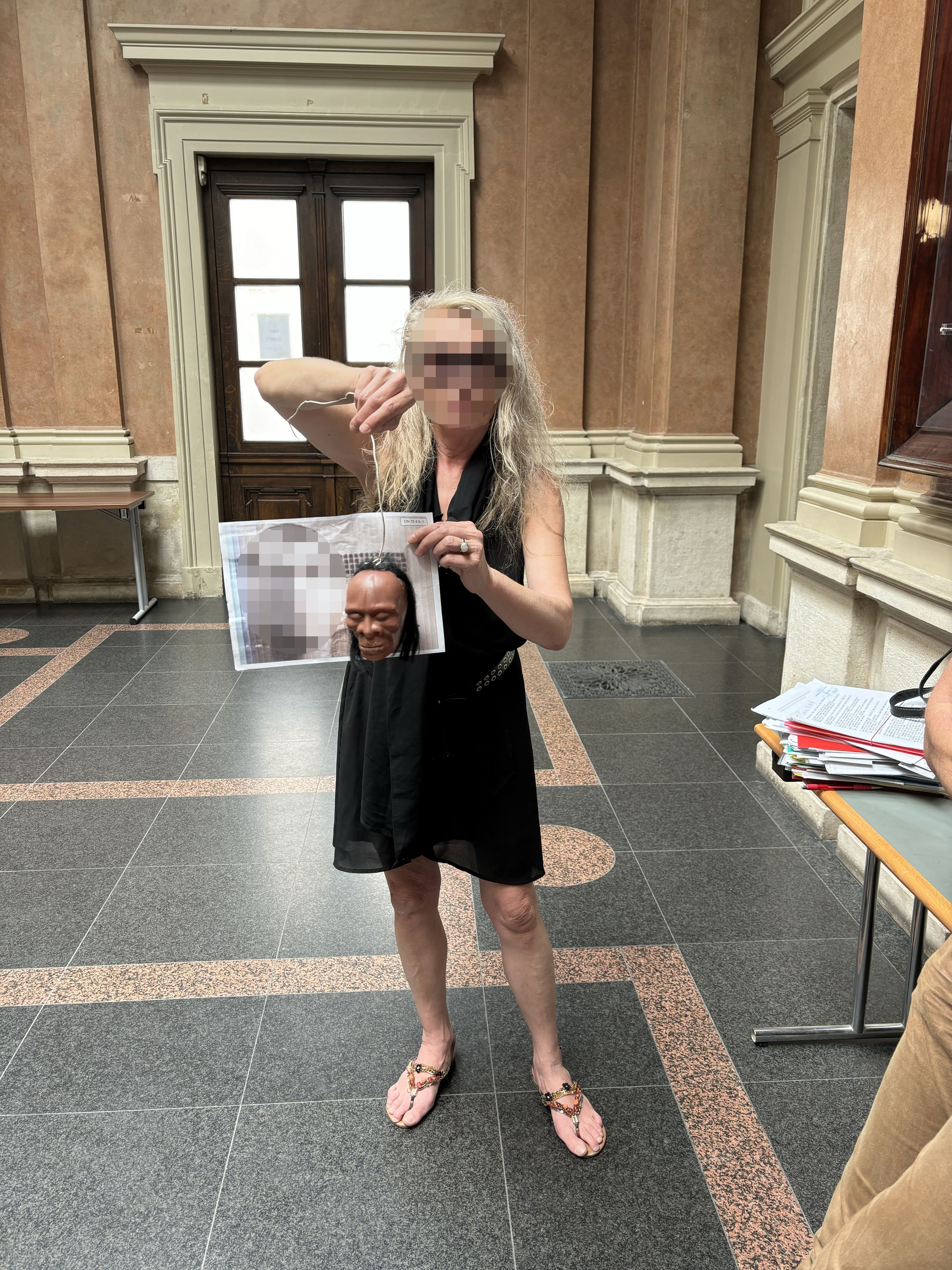 Die Mutter des Betroffenen mit Puppenkopf und Foto des Kindesvaters.