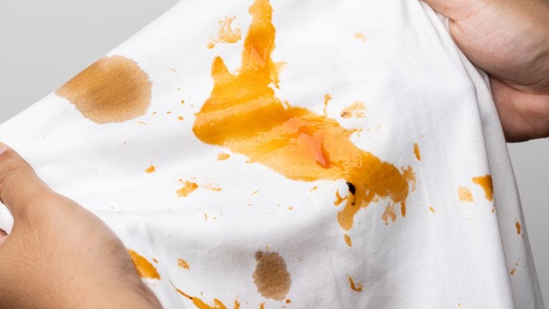 White cotton shirt So many stains and dirt. Stained ketchup The man's hand held the shirt and opened it to look at the dirt.