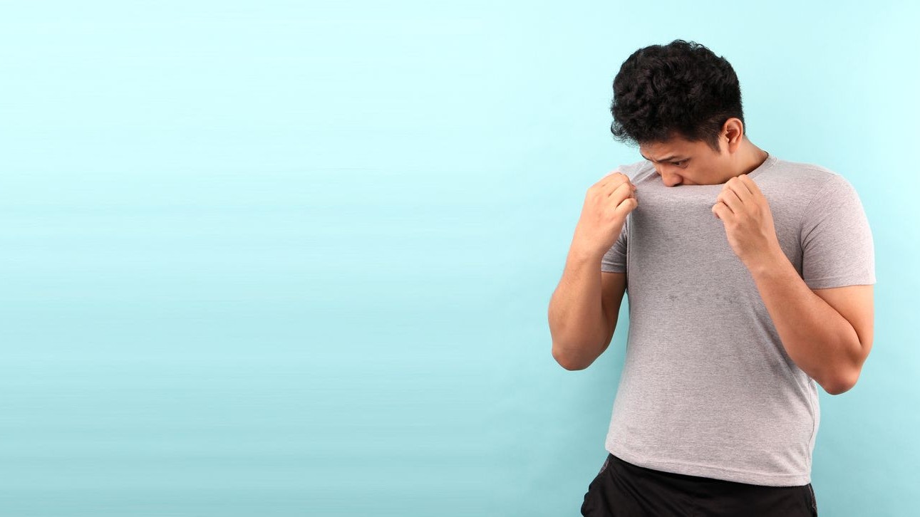 Asia Man sweating excessively smelling bad isolated on bluebackground in studio With copy space.
