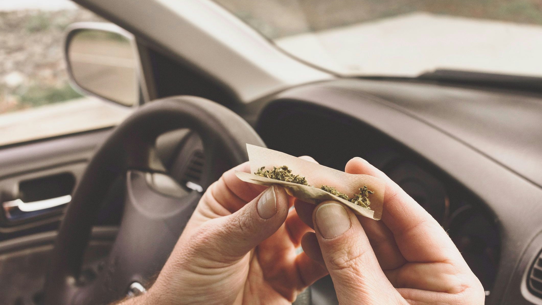 Stock photo of a man smoking marijuana in a vehicle driving a car under the influence of cannabis.