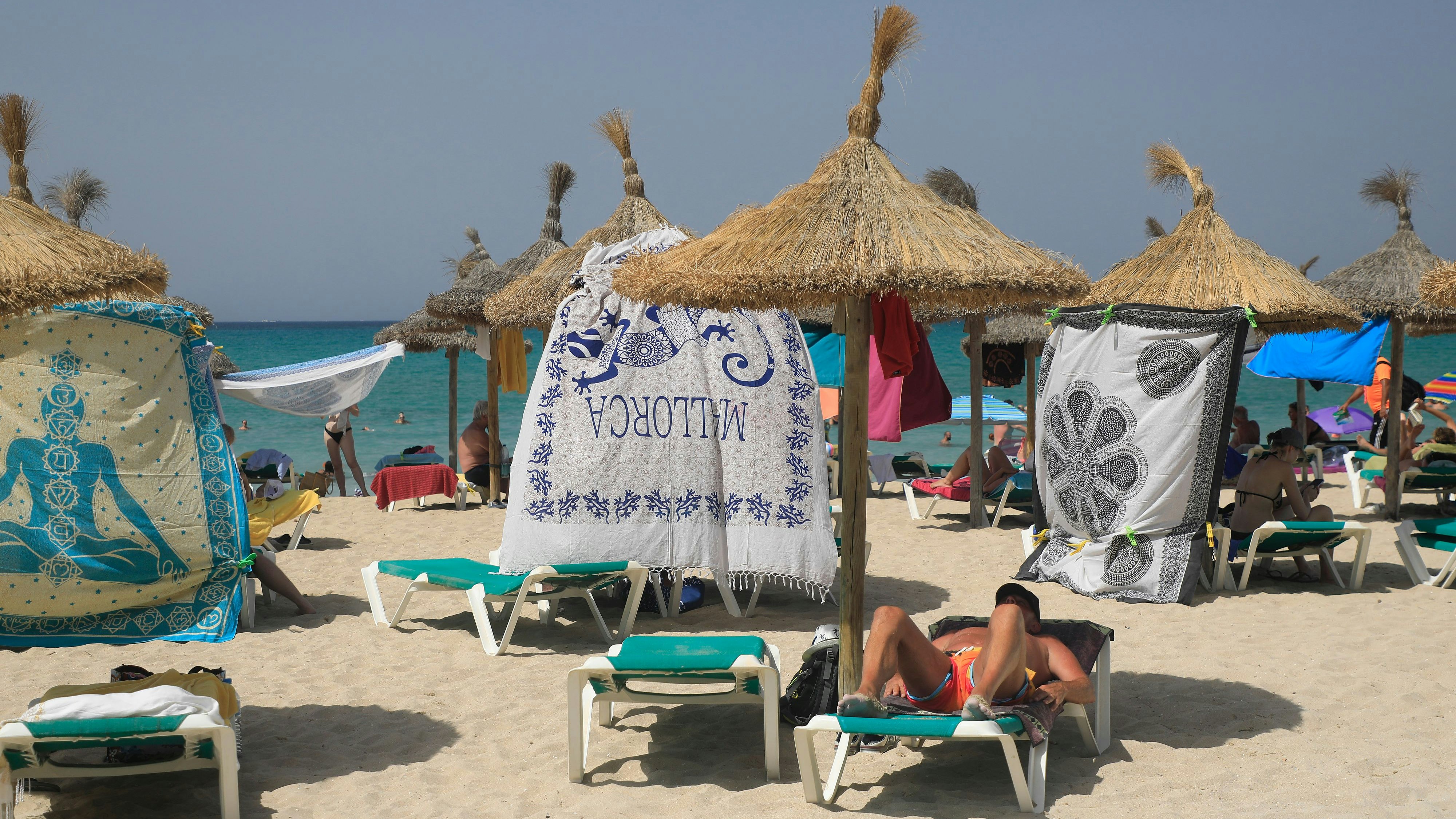 Download von www.picturedesk.com am 16.07.2024 (12:03).  18 July 2023, Spain, Palma de Mallorca: People protect themselves from the sun with beach towels on the beach of Arenal in hot temperatures. For the north and east of the Spanish Mediterranean island of Mallorca, the national weather service Aemet announced maximum temperatures of at least 43 degrees. The peak of the third heat wave of the summer in Spain makes locals and tourists in the popular vacation destination sweat. Photo: Clara Margais/dpa - 20230718_PD6419 - Rechteinfo: Rights Managed (RM)