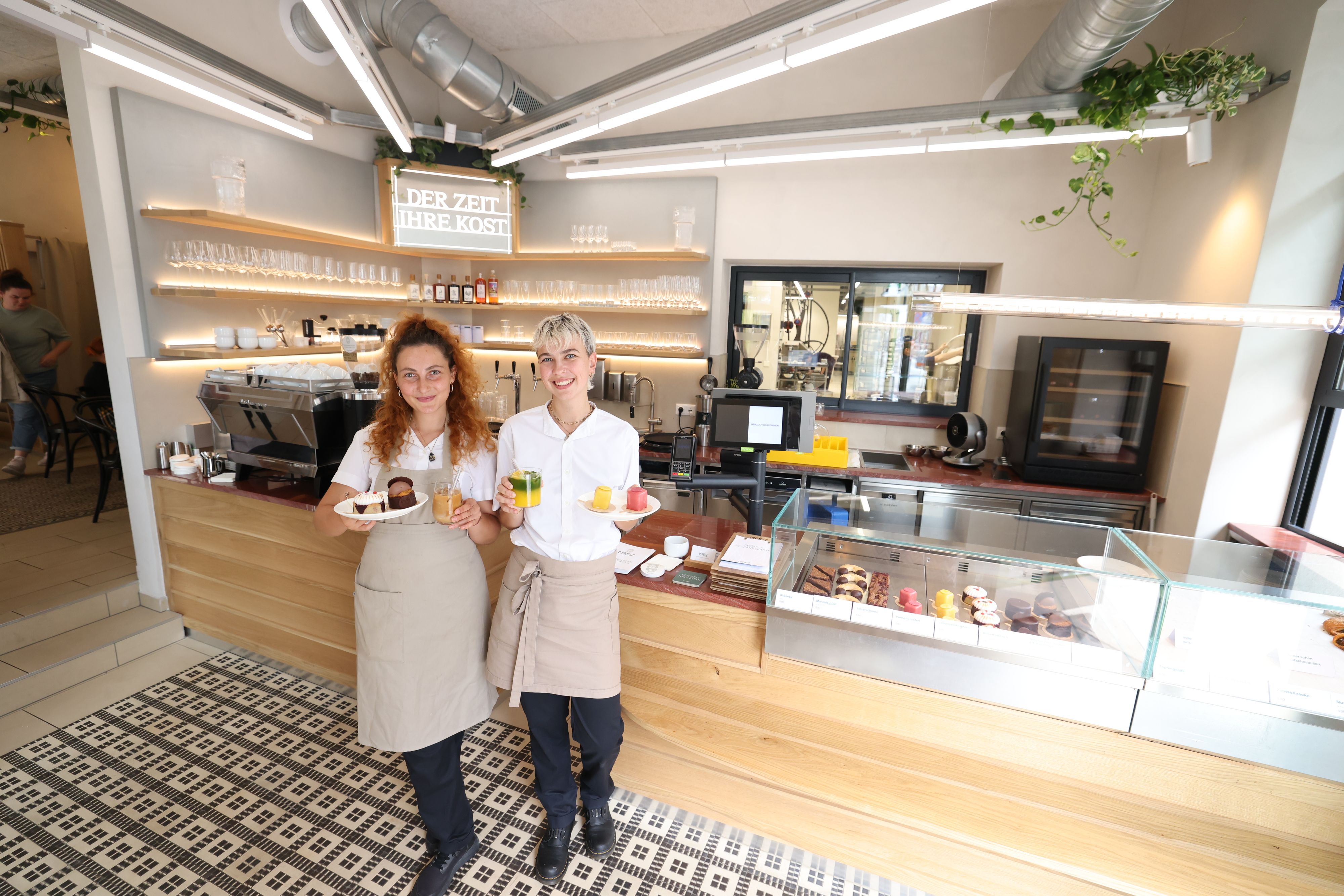 Die beiden Barista Celia und Sandra mit den Topsellern: Birnenbaisser, Sachertorte modern, Eiskaffee, Macha Orange Latte, Limoncellokrapferl und Punschkrapferl (v.li.)