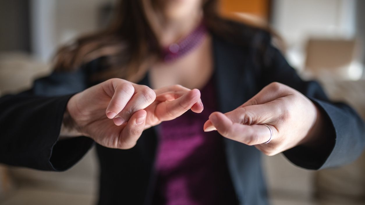 Woman at home sitting on a sofa doing a sign language.