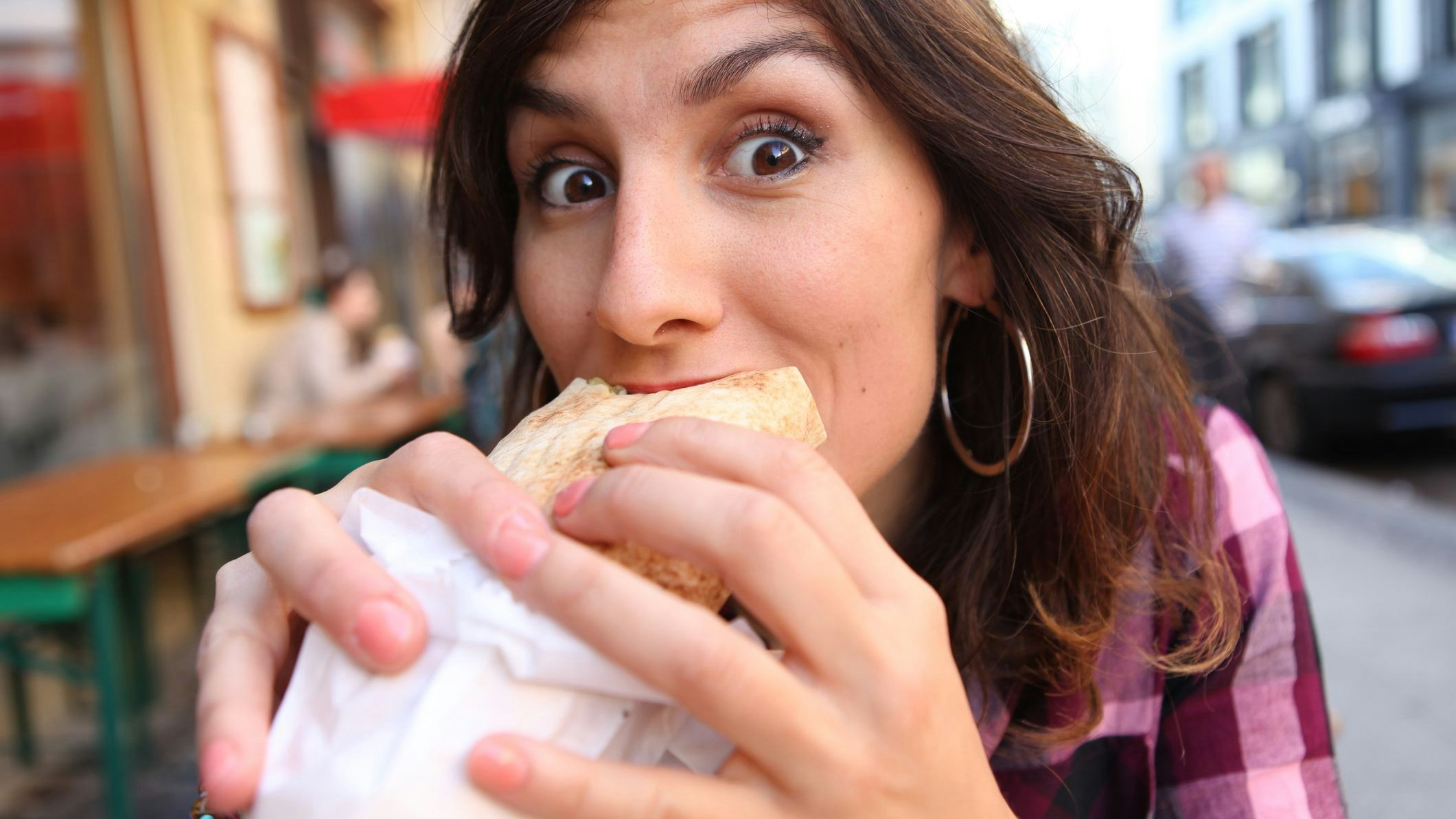 Young Woman eating the typical Berliner doner kebab, sitting in any restaurant at the street