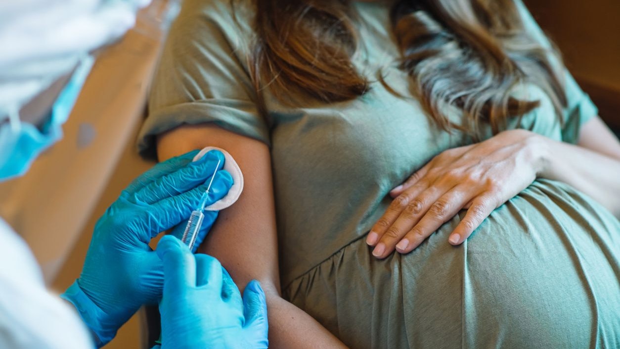 Pregnant woman getting vaccine at home. COVID-19 vaccination concept.