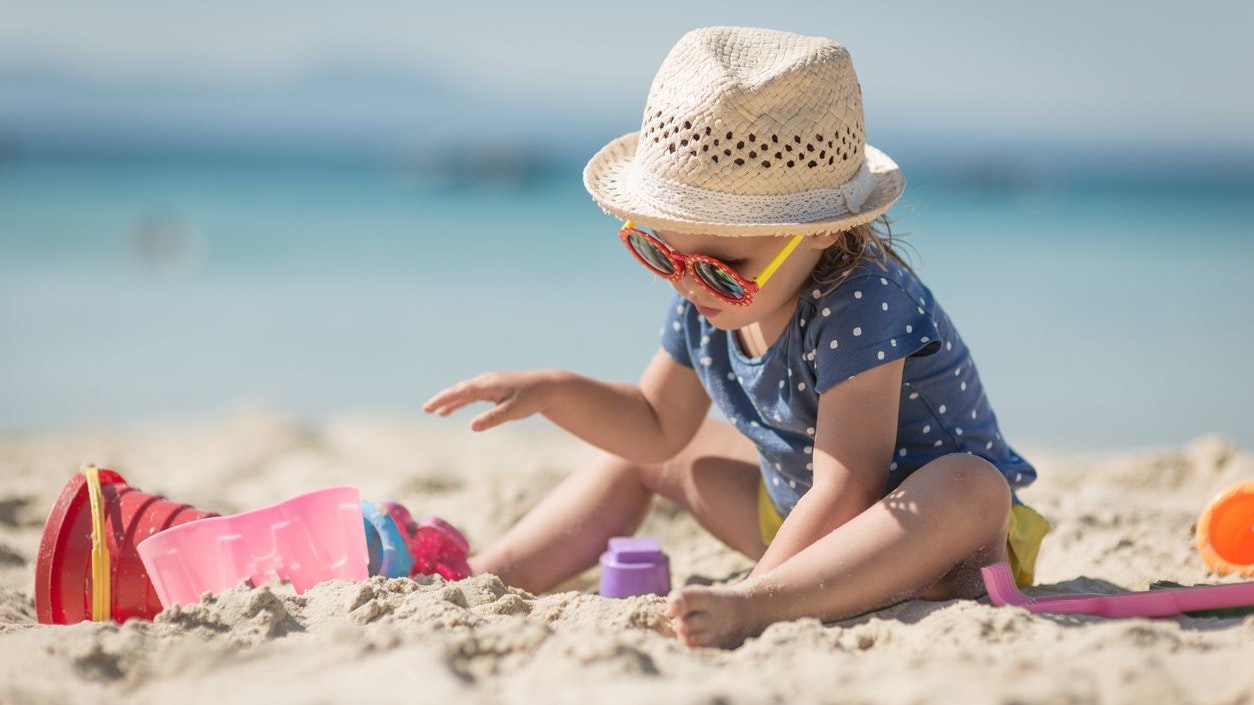 Caucasian littplayng beach toysle girl with hat