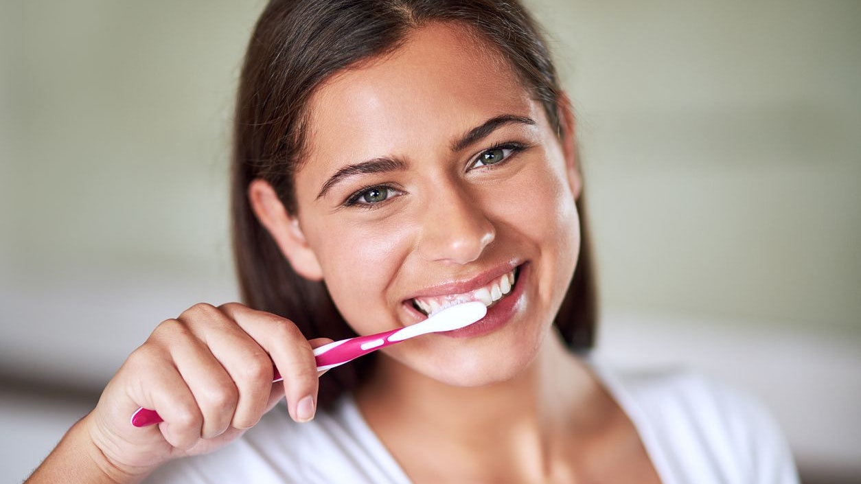 Portrait of a beautiful woman brushing her teeth in the bathroom at home