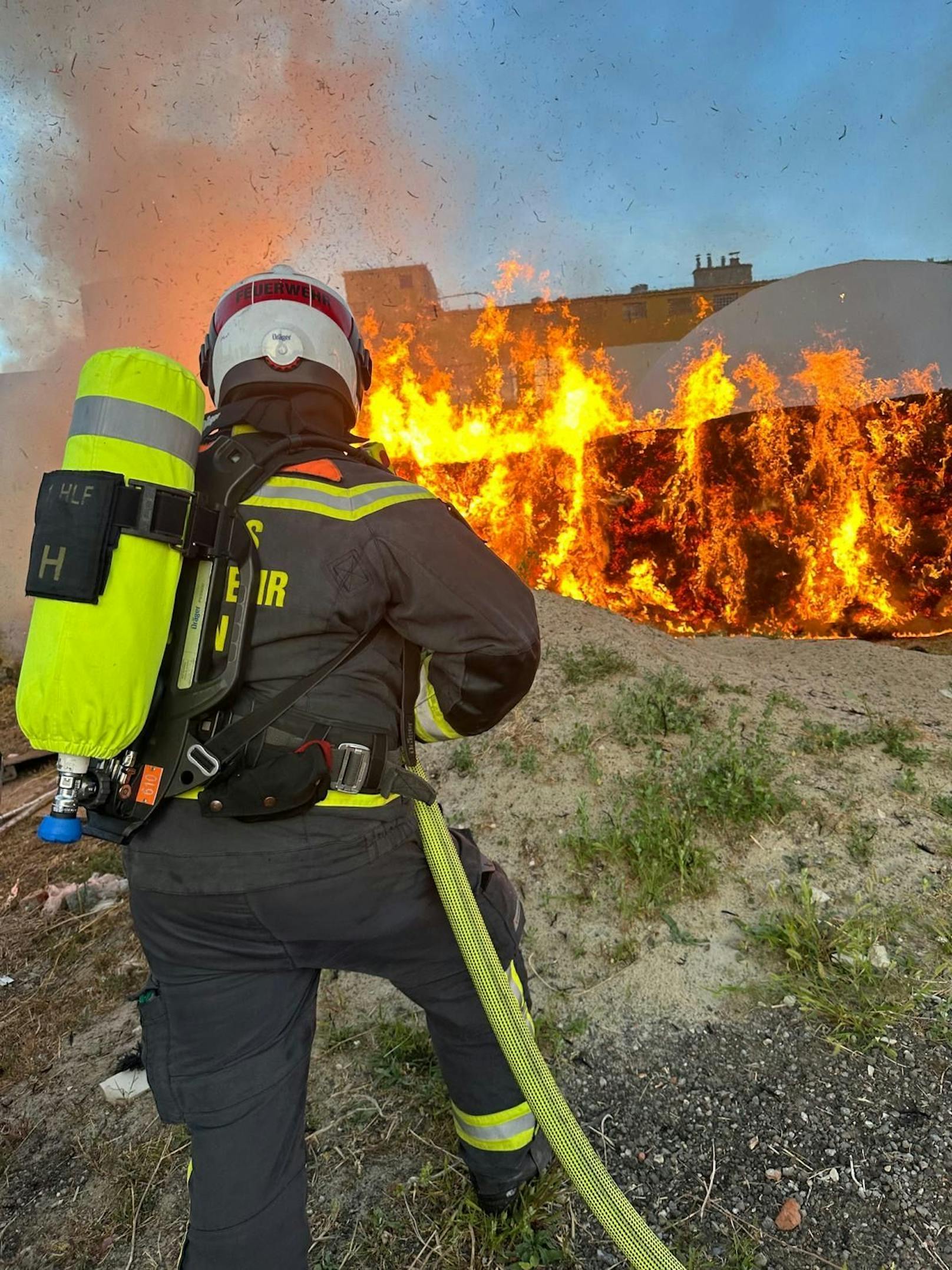 Mit sieben Löschleitungen bekämpfen Feuerwehrleute, teilweise unter Atemschutz, den Brand einer nicht öffentlichen Eventlocation auf einem Firmenareal.