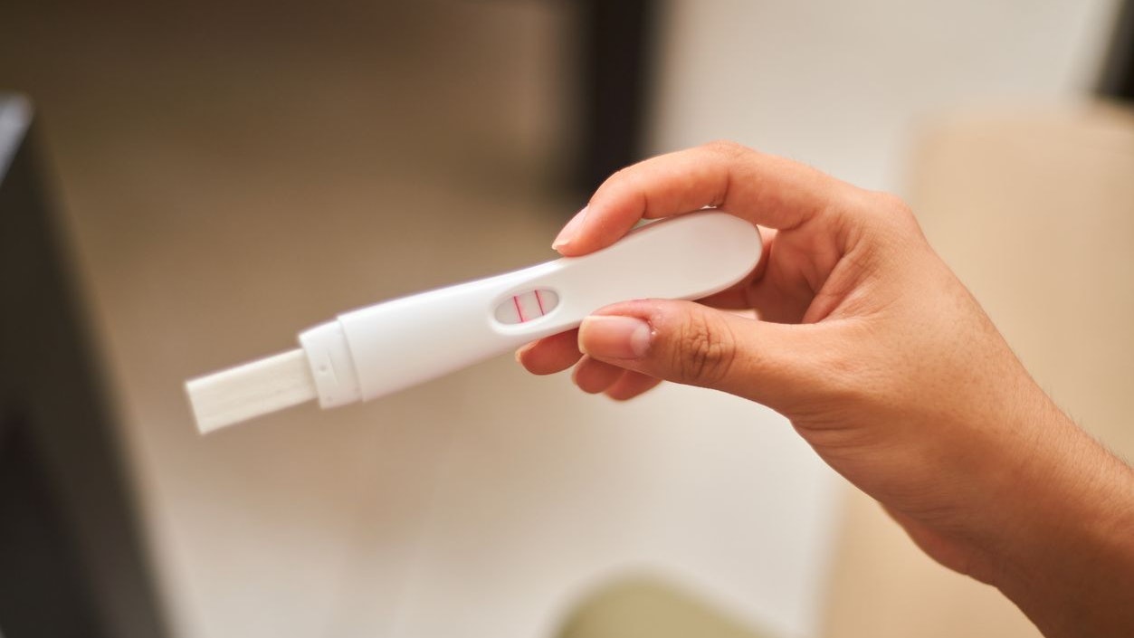 Close up of young latina woman looking at positive pregnancy test. Concept, conscious motherhood, family planning.