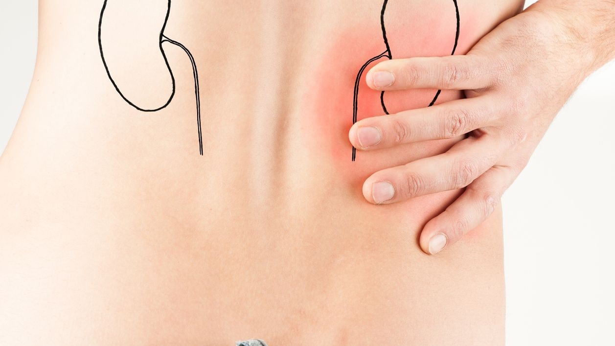 Young male adult holding his back because of pain. He may suffer from a musculoskeletal or kidney disease.