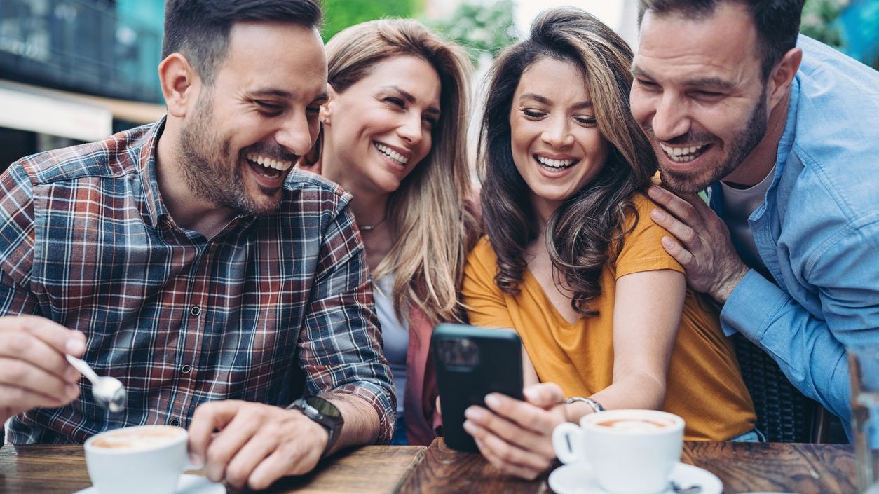 Group of friends using cell phone in a sidewalk cafe