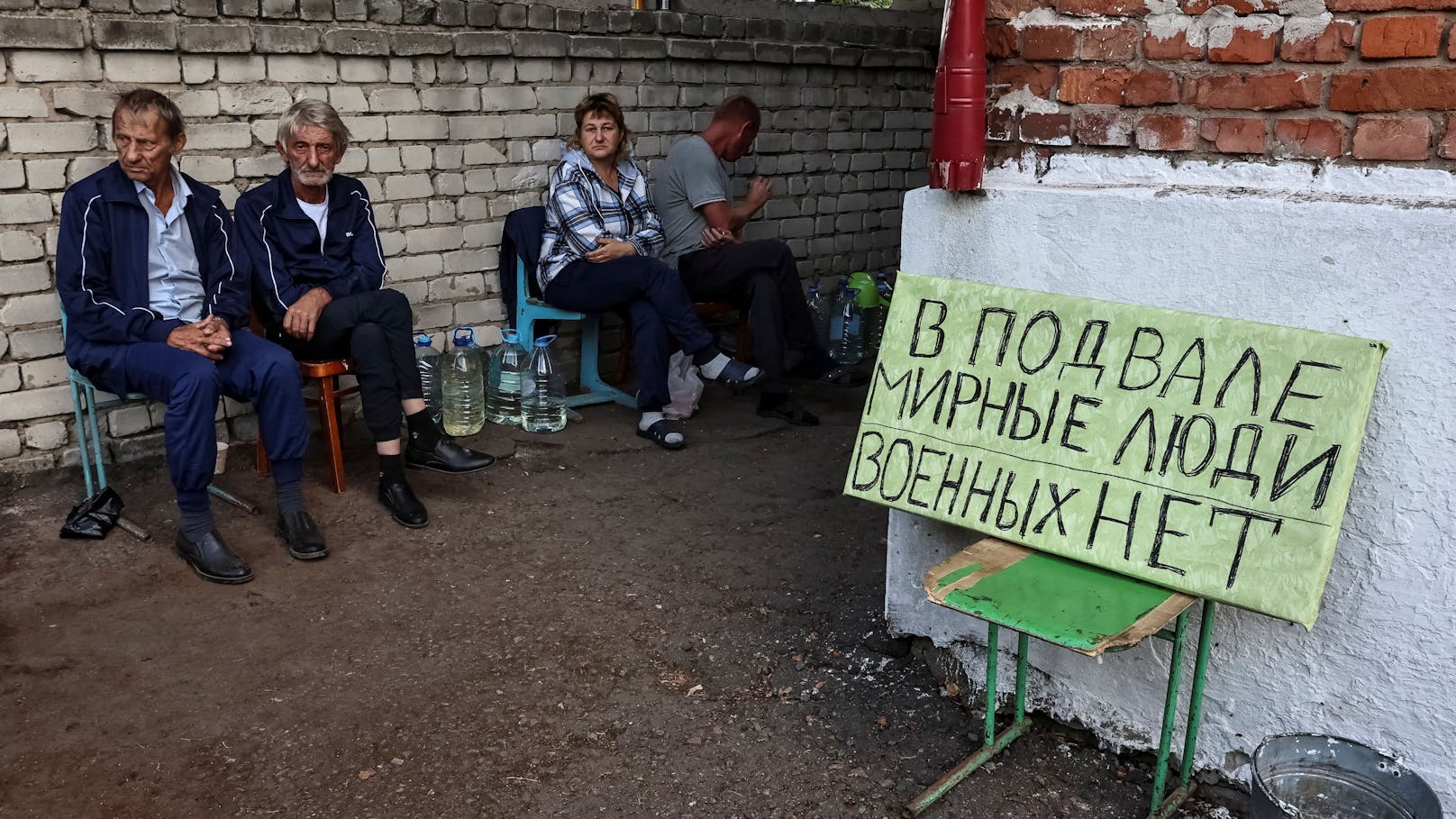 Bewohner der russischen Stadt Sudzha, die derzeit von der Ukraine kontrolliert wird. Neben ihnen ein Schild mit der Aufschrift: "Im Bunker sind friedliche Menschen, es gibt keine Soldaten".