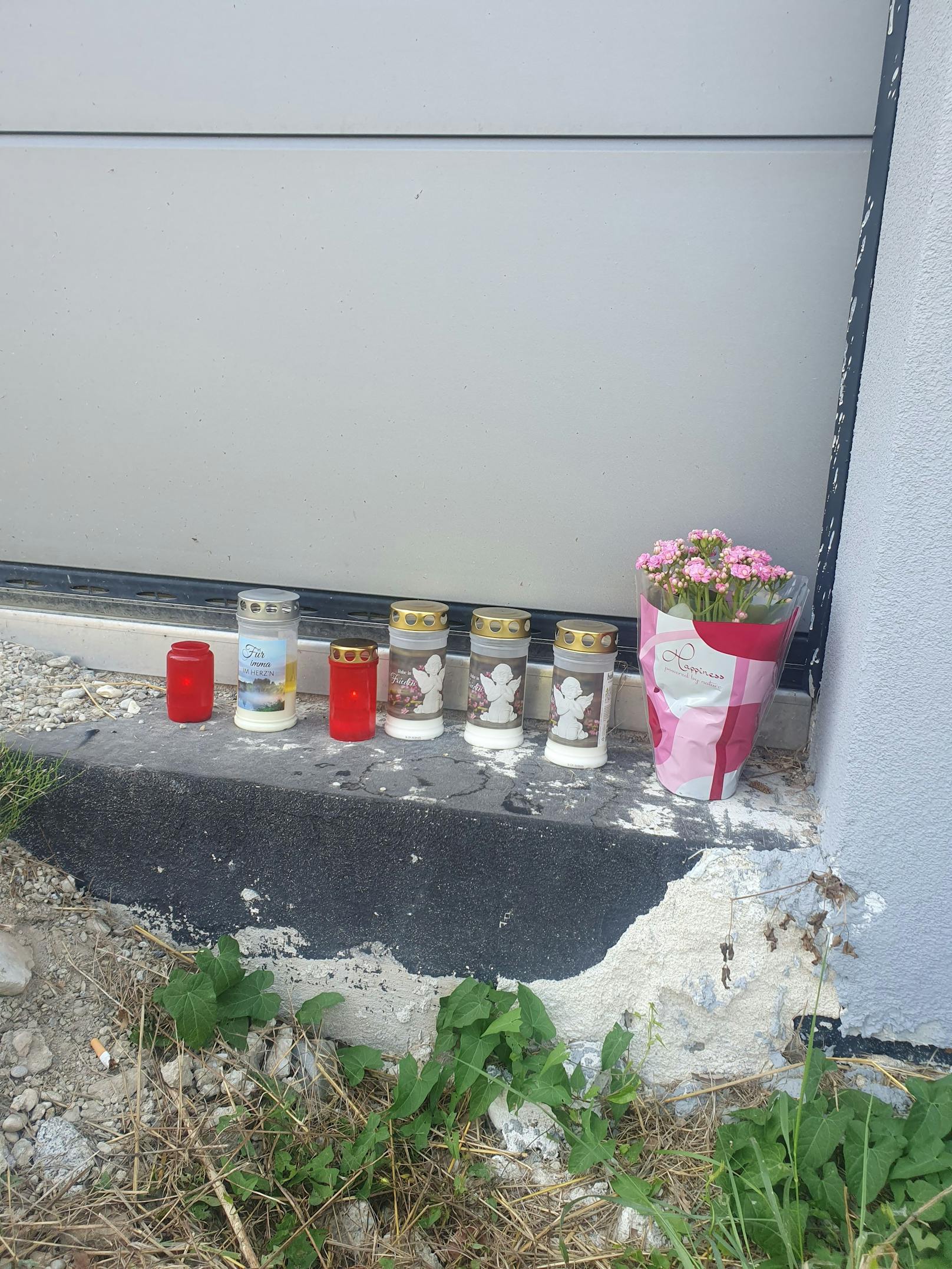 Blumen, angezündete Kerzen bei der Garageneinfahrt