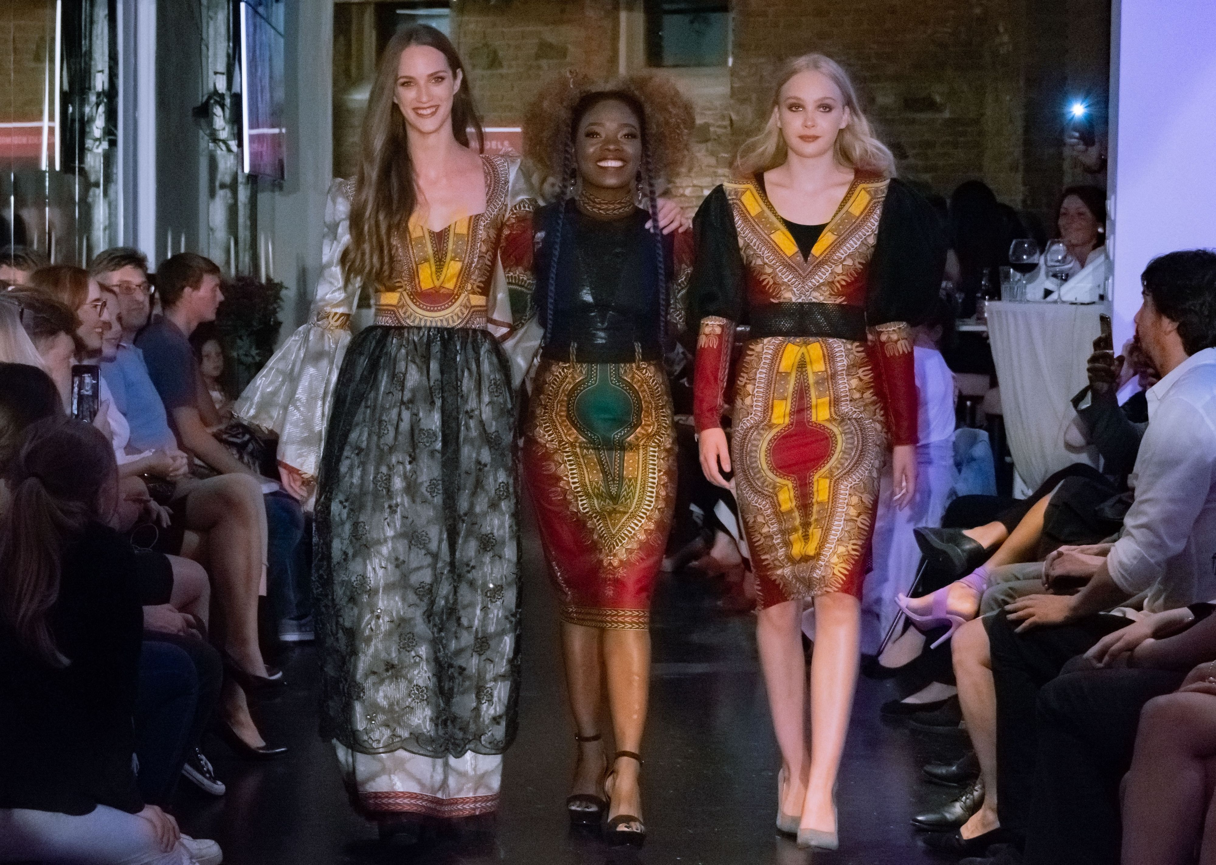 Die Wiener Designerin Barbara Alli, flankiert von zwei Models, bei einer Modeschau.