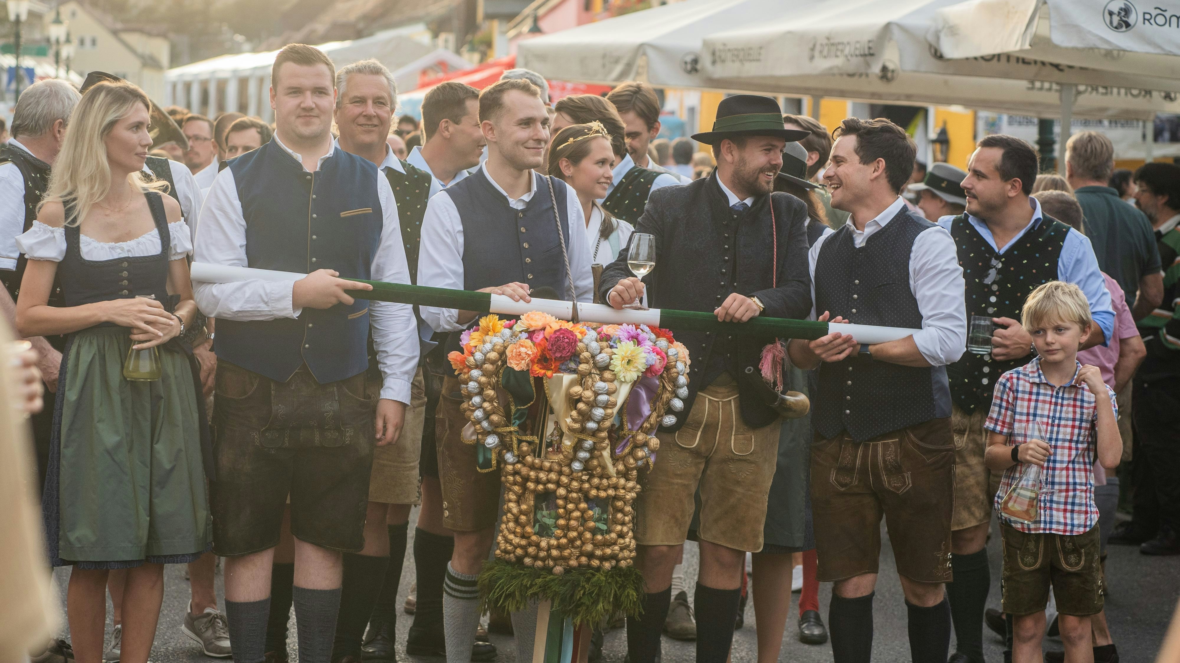 Die traditionelle Hauerkrone wird durch den Kirtag getragen. Juniorchef Gerry Wolff (Mitte) kümmert sich um das traditionelle Anspielen, bei dem Stammgäste und Heurigen-Familien begrüßt werden.