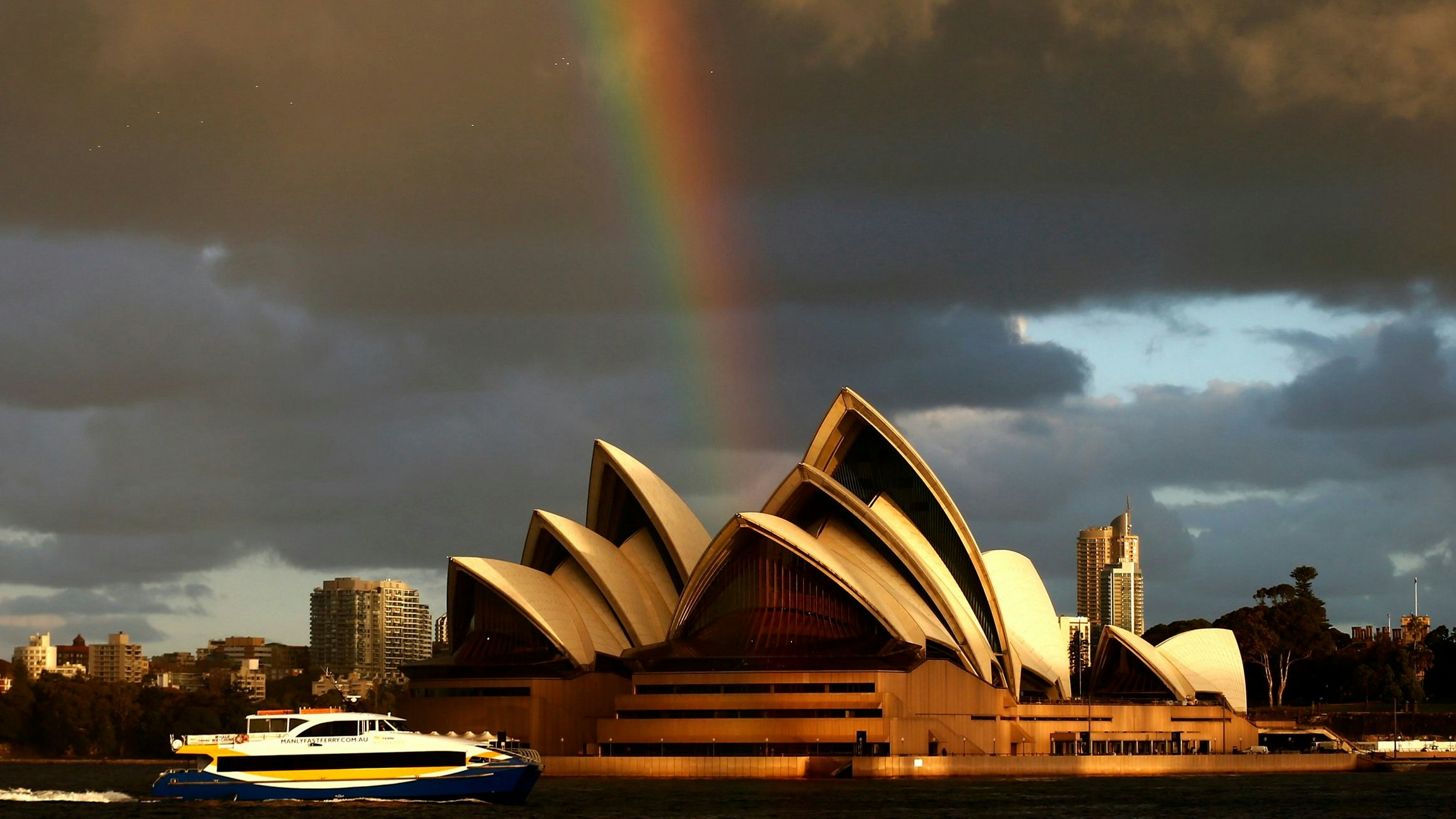 A passenger ferry navigates past the Sydney Opera House, as a rainbow is seen in the sky, on a sunny winter afternoon in central Sydney July 31, 2013. Sydney has experienced one of the warmest Julys on record with average daytime temperature of more than 19 degrees Celsius (66 degrees Fahrenheit), local media reported. REUTERS/Daniel Munoz (AUSTRALIA - Tags: ENVIRONMENT SOCIETY MARITIME TPX IMAGES OF THE DAY)