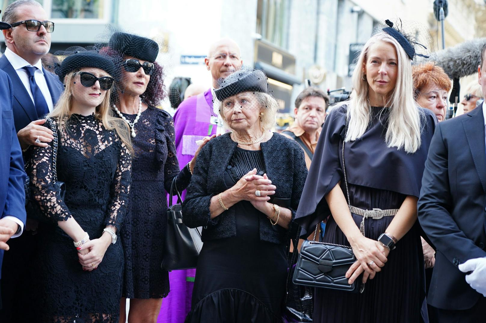 Während der Sarg in den Wagen geladen wird, lauschen Lugners Angehörige der Blaskapelle.