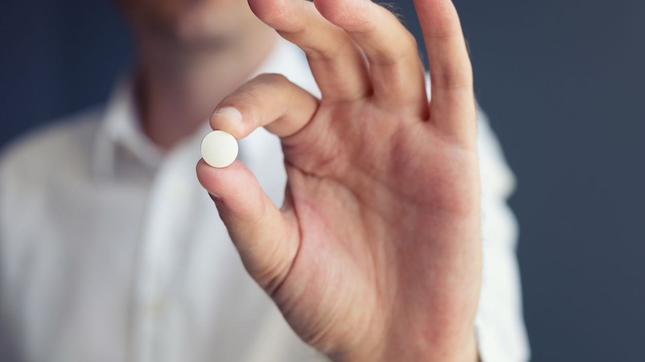 Midsection Of Man Holding Pill