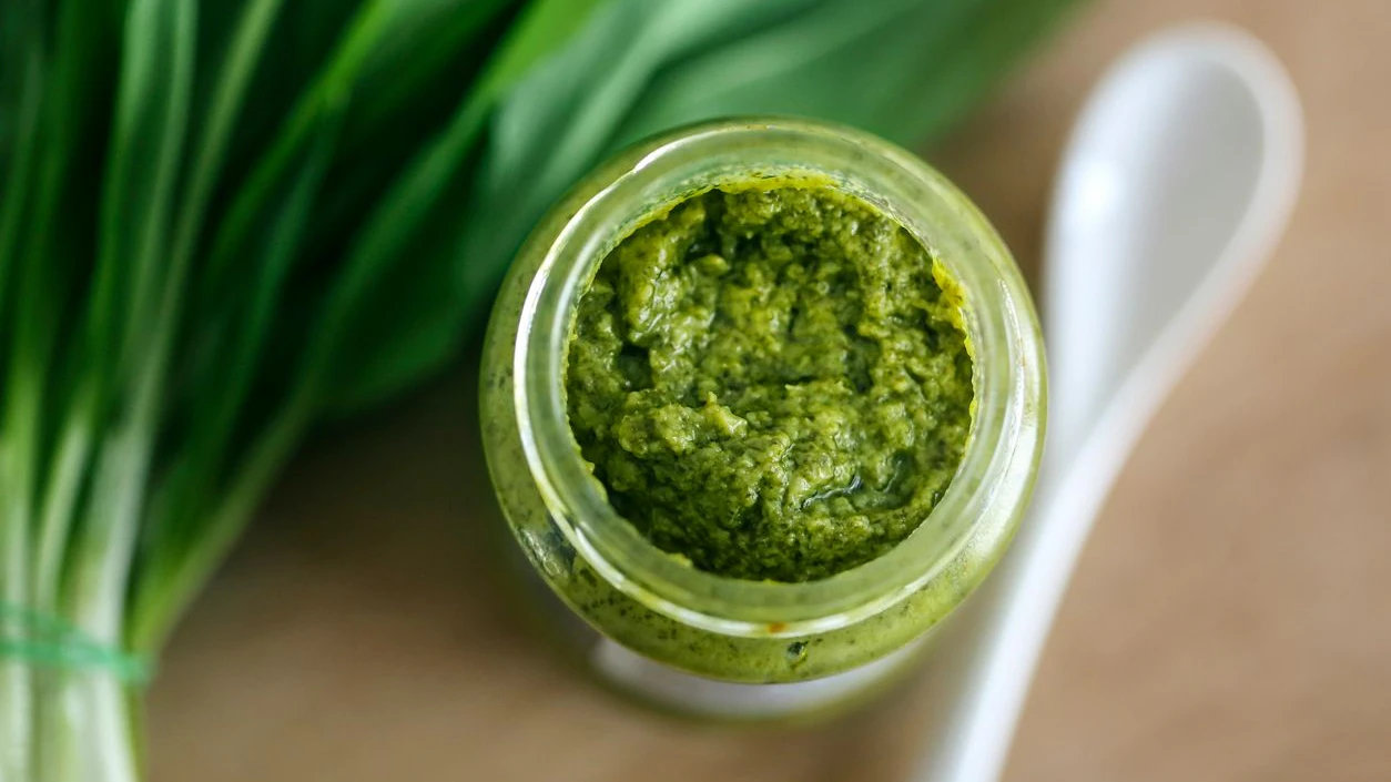 Homemade pesto made from fresh ramsons or wild garlic on wooden background.