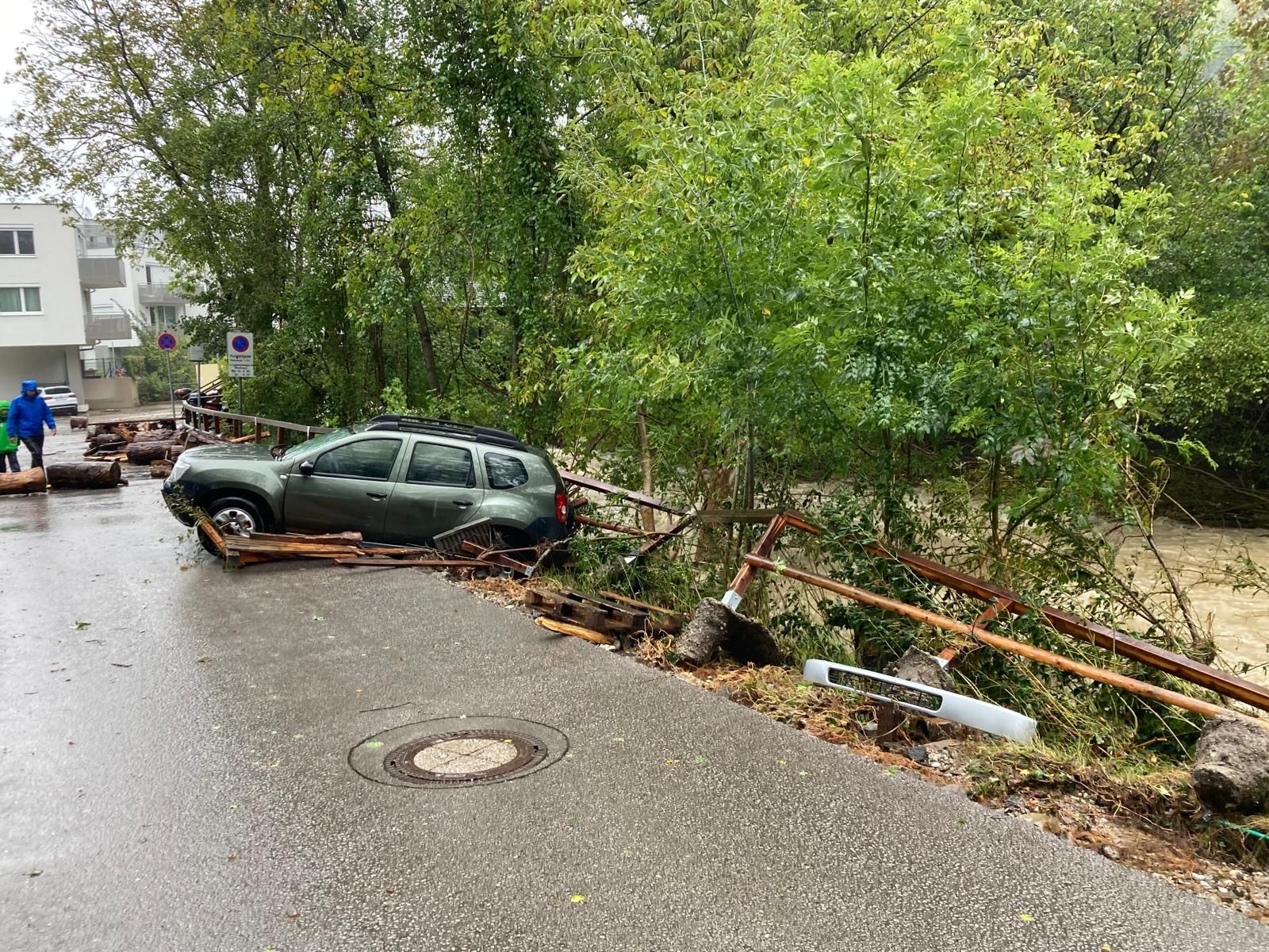 Mitten im Katastrophengebiet droht aufgrund des Unwetters ein Auto den Hang runter in den Fluss zu rutschen.