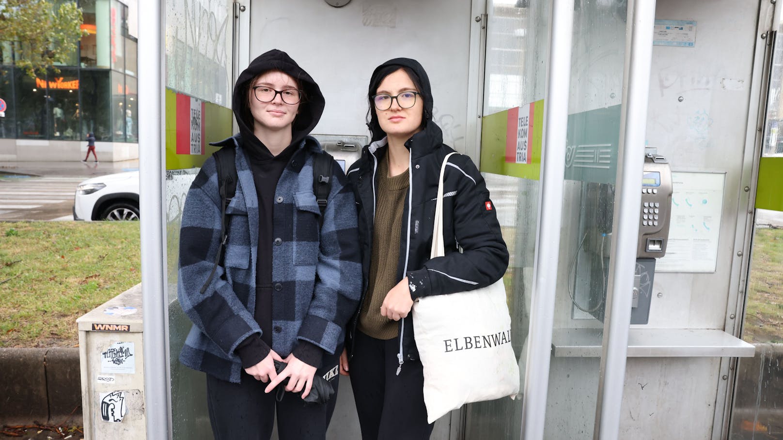 Während sie auf den Schienenersatzverkehr warteten, schützen sich Selina und Anna Maria vor Wind und Regen.