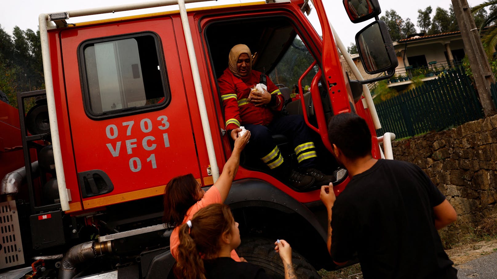 Einheimische versorgen einen Feuerwehrmann bei der Bekämpfung von Waldbränden in der Nähe von Doninhas, Portugal.