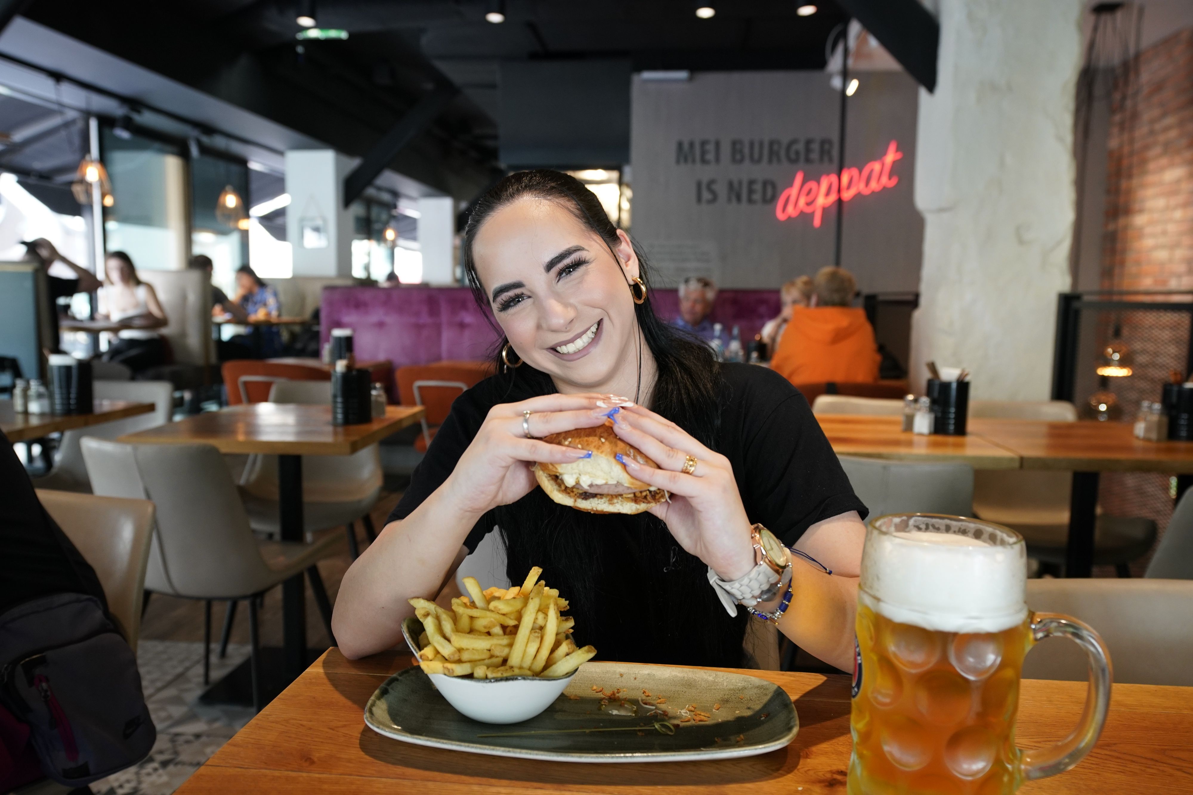 Le Burger Mitarbeiterin Kristina S. mit der neuen Burgerkreation: XXL-Bratwurst zwischen zwei Brothälften und Kren dazu