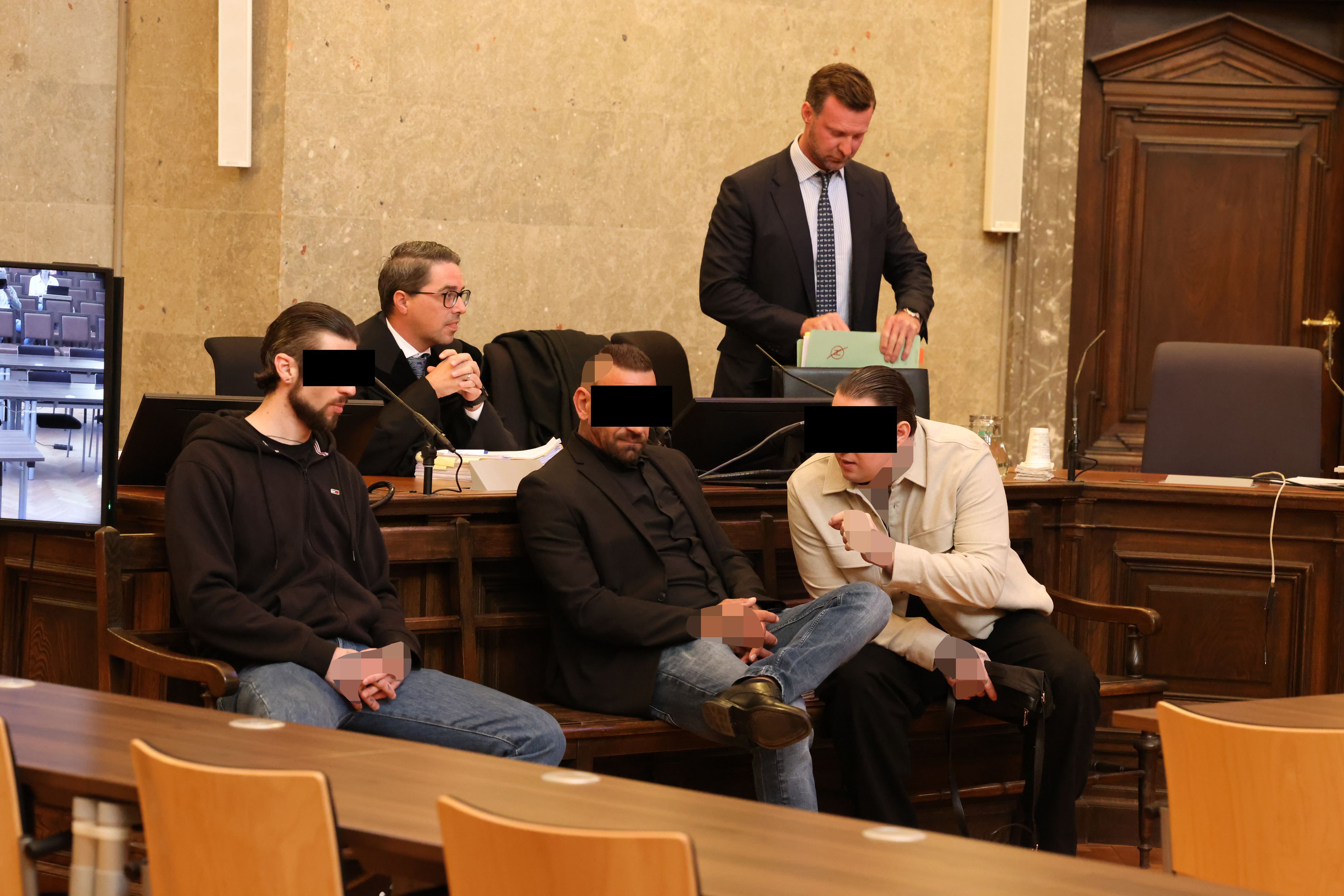 Die drei Angeklagten mit Anwalt Philipp Wolm (r.). 