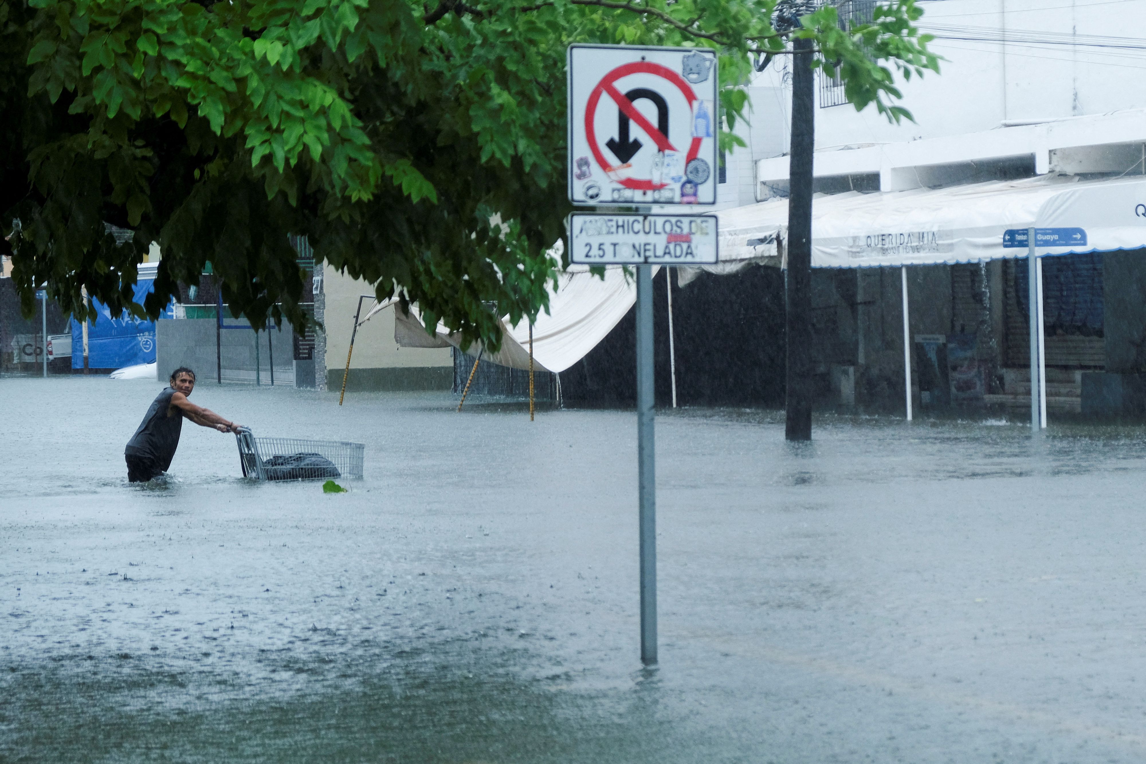 Ein Mann schiebt einen Wagen auf einer überfluteten Straße in Cancun, Mexiko, während der Regenfälle, die durch den Tropensturm Helene verursacht wurden.