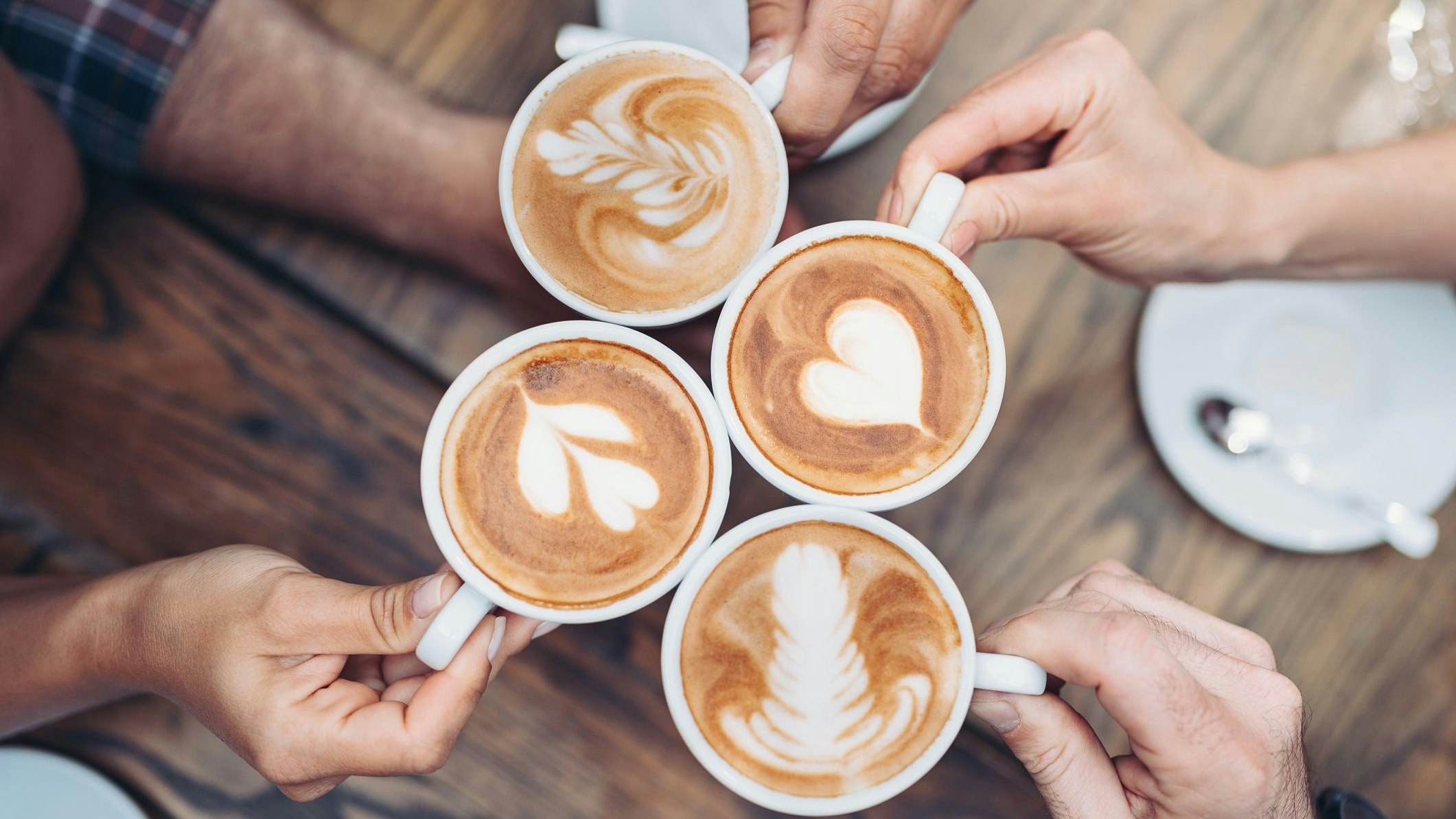 Above view of hands holding cappuccino cups