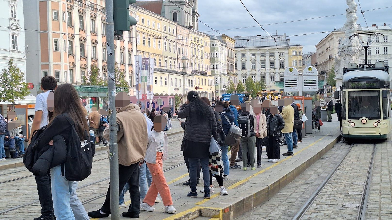 Am Linzer Hauptplatz warten Menschen auf ihre Bim.